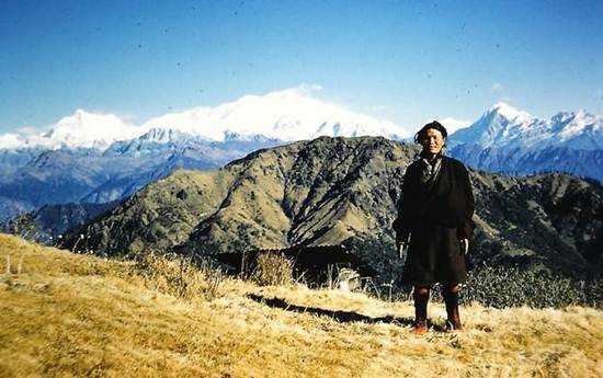 Tibetan stands at attention, boots intact, near the Phalut hut, Mt Kanchenjunga behind